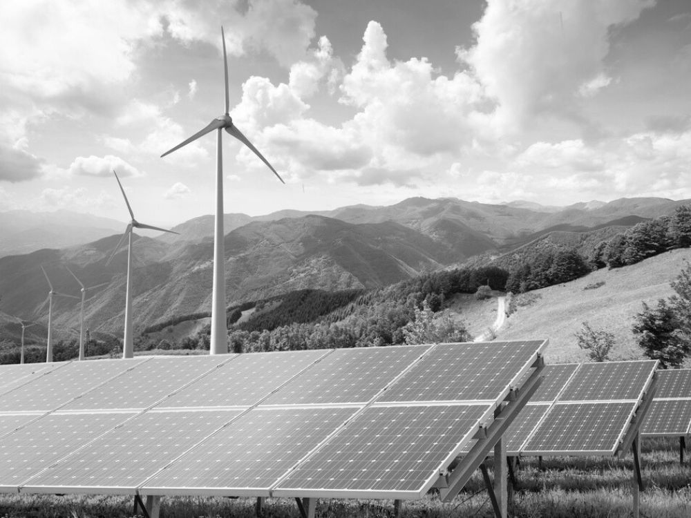 Modern wind turbine and solar panels set against a scenic countryside landscape, showcasing renewable energy technology.